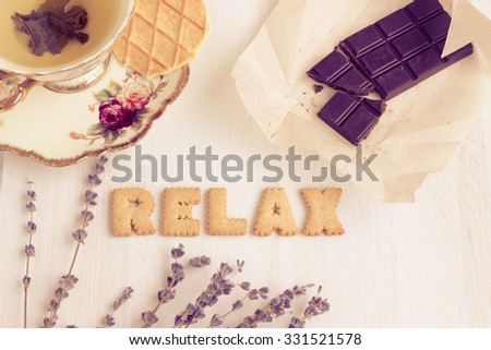 Word RELAX. Still life image with biscuits, organic chocolate and vintage cup of green tea white wooden background. Top view collage made of biscuits. Retro toned and instagram filtered image. Royalty-Free Stock Photo #331521578