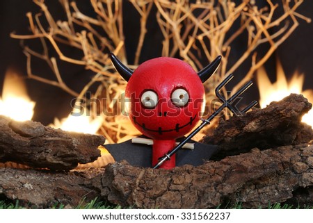 Halloween Devil Doll on black background with dead trees and fire.