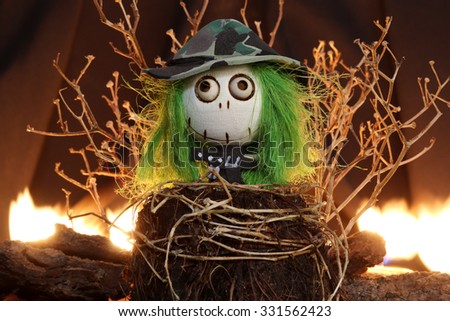 Halloween Devil Doll on black background with dead trees and fire.