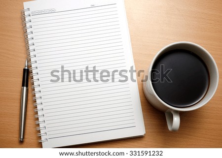 Blank notebook, pen and a cup of coffee on wooden table, home or office environment concept for background.