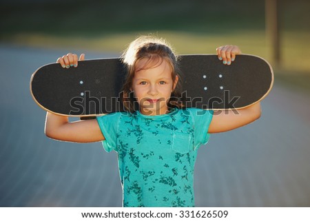 photo of cute little girl with skateboard outdoors