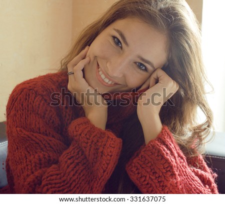 young pretty real woman in red sweater and scarf all over her face smiling at home, winter positive