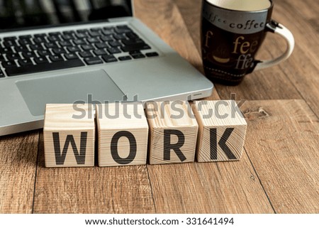 Work written on a wooden cube in front of a laptop