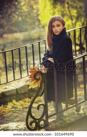 Portrait of a beautiful young girl in autumn park. Toned in warm colors