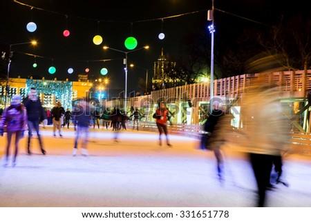 People are skating in the park on winter skating rink