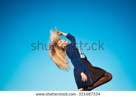 close-up portrait on a background of blue sky autumn lifestyle of young beautiful girl with stylish blonde with long hair blonde outdoors in coat and scarf  is laughing and happy