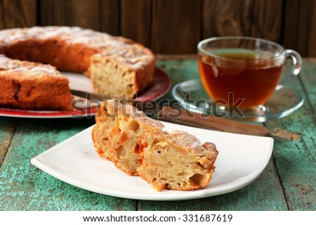 Homemade apple cake and black tea in glass cup on old wooden table