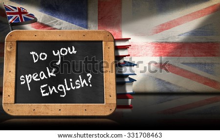 Do You Speak English - Blackboard and Books / Blackboard with wooden frame and text Do you speak english? A stack of books on a wall with Uk flag Royalty-Free Stock Photo #331708463