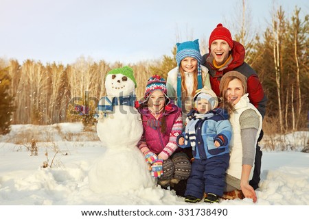 portrait of a cheerful family with snowman. happy children and parents in the winter outdoors