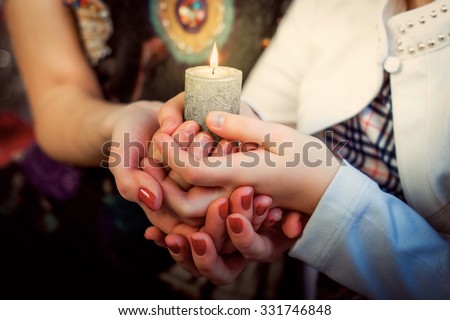 Christmas photo: hands of mother and daughter holding a candle