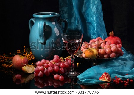 Still-life with wine, fruit and a dark blue jug on a black background
