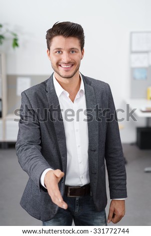young smiling businessman with his hand outstretched for a handshake