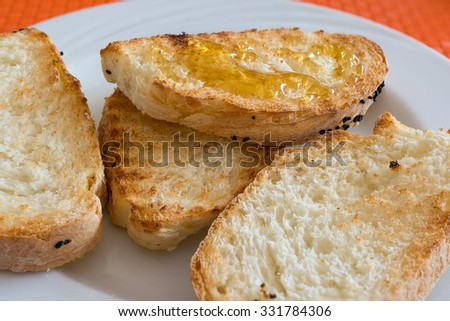 in the picture slice bread toasted with honey on white dish at restaurant.