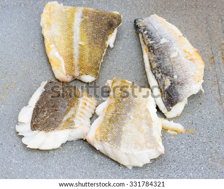 Pictured three fillets of sea bream and codfish cooked on the grill outdoor.