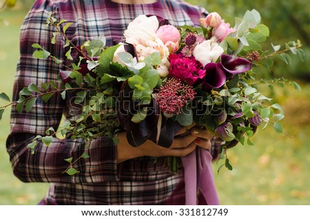 Cool bridal bouquet. Bride in a plaid dress holding a beautiful stylish bouquet of flowers.