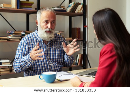 boss explaining something to young worker in his office