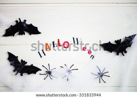 Halloween Letters cut out from the Magazines, Bats, Web and Black Spiders on White Wooden Background