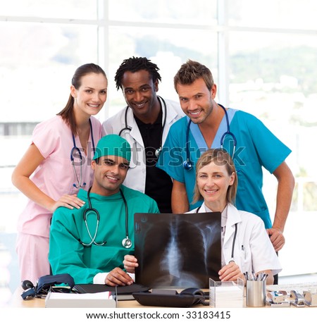 Medical team examining an X-ray in hospital and smiling at the camera
