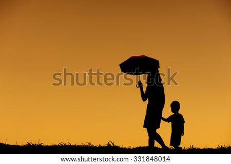 silhouette of a mother and son playing outdoors at sunset with copy space