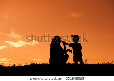 silhouette of a mother and son playing outdoors at sunset with copy space