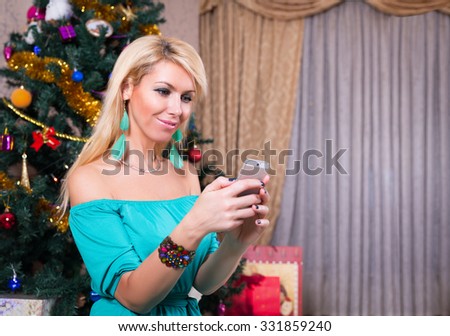 Pretty woman taking selfie photo on mobile phone near Christmas tree