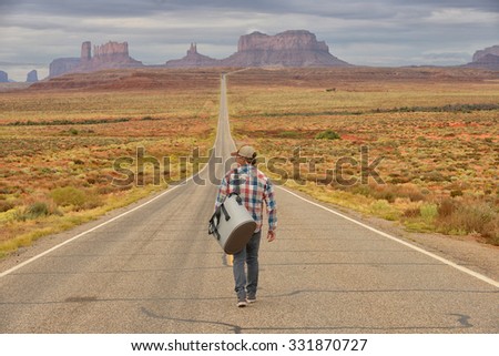 Wanderer or loner in Monument Valley walking down an empty road Royalty-Free Stock Photo #331870727
