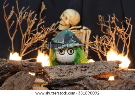 Halloween Devil Doll on black background withhuman skeleton, dead trees and fire.