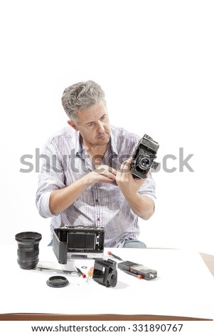 Man repairing an old camera
Male repairing an old camera at his workplace on white background