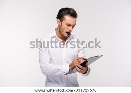 Portrait of a handsome businessman making notes on clipboard isolated on a white background