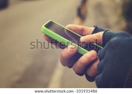 Man with gloves using cellphone outdoors.
