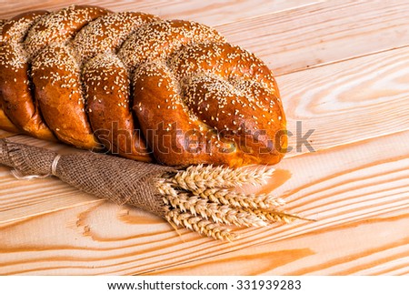 Two whole fresh challah bread with poppy and sesame seeds and honey wooden background