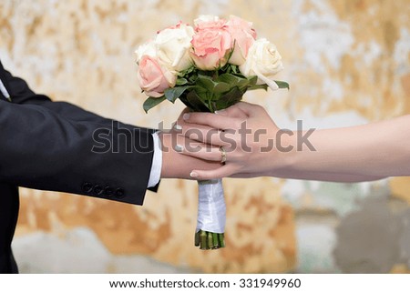 Couple hands holding a bride's bouquet over the grunge background