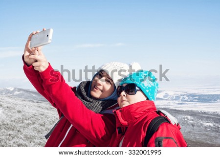 Mother and child take the selfie photo in winter landscape. Seasonal tourism.