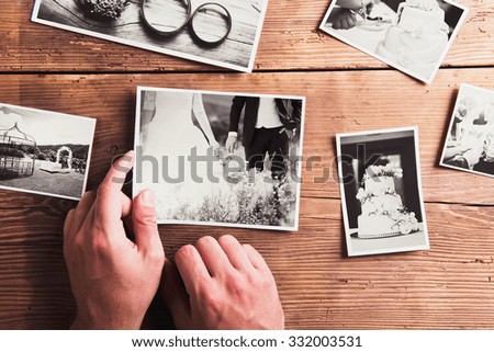 Wedding photos laid on a table. Studio shot on wooden background.