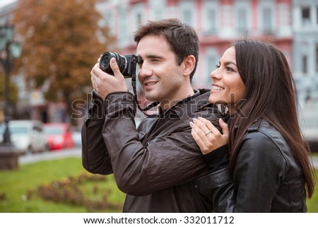 Portrait of a smiling couple traveling and making photo on camera in old european city