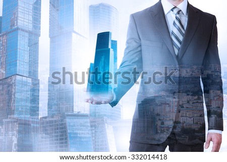 Businessman holding 3d city model on cityscape background