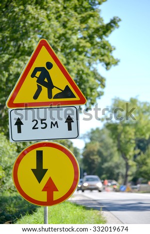 Road signs "Roadwork", "Advantage before oncoming traffic" against a highway