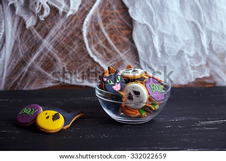 Dark picture of bowl of Halloween cookies at spiderweb and ghost background.