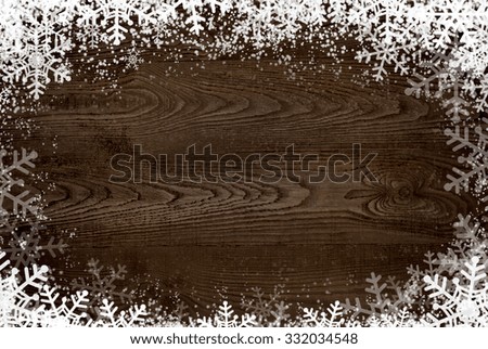 Winter background - snow and snowflakes at dark wooden surface.