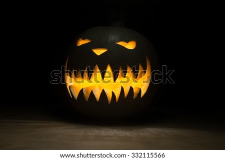 Spooky pumpkin on halloween on table with light inside on dark