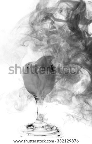 Abstract art. Gray smoke hookah in cocktail glass on a white background. Witch potion background for Halloween. Unusual bar drink. Drink in the glass with the effect of dry ice.