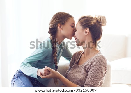 Pre teen daughter kissing her mom, positive feelings, good relations.