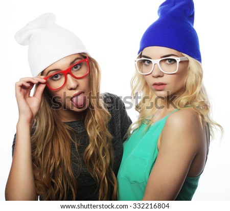 Close up lifestyle portrait of two pretty teen girlfriends smiling and having fun, wearing hipster clothes, hats and glasses, positive mood.