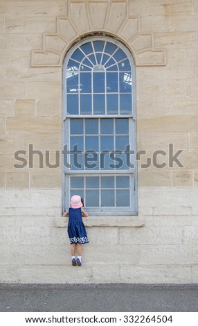 Curious girl looking through an arched window. 