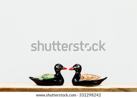 Ceramic black duck figurines on wooden table on white background