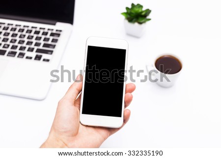 Hand holding smart mobile phone on wooden table and light blurred background