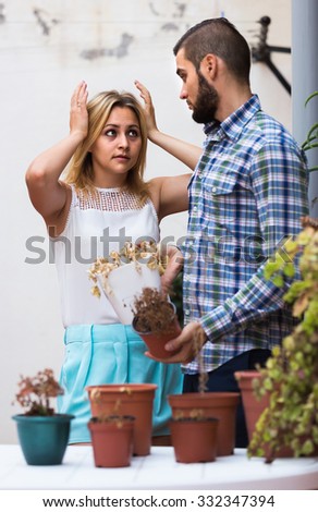Young american man making excuses for not watering girlfriends flowers