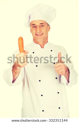 Male chef in uniform holding a carrot showing ok sign