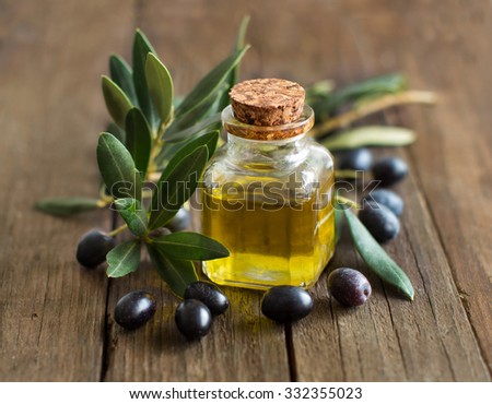Olive oil and fresh olives on rustic wood background