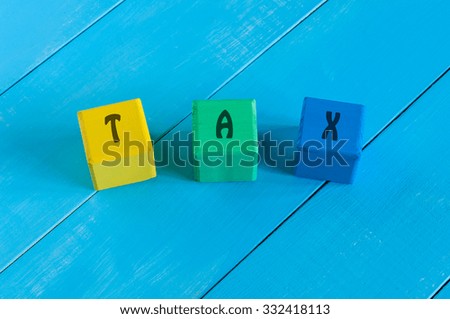 Tax - sign on color wooden cubes with light blue wood background